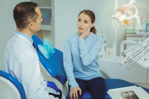Dentists performing a procedure on a patient in a clinic, addressing concerns about tooth sensitivity after a crown.