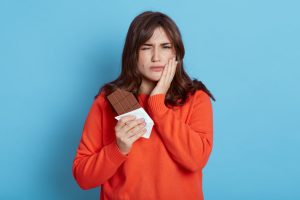 Woman suffering from toothache after eating chocolate.
