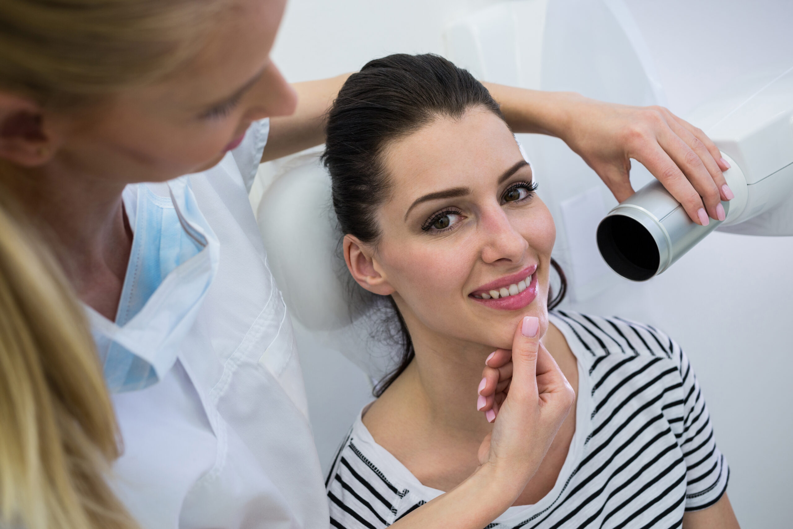 Dentist examining a patient’s smile while using dental equipment.