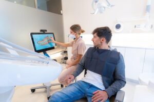 Dentist showing a patient a digital dental scan in a modern exam room.