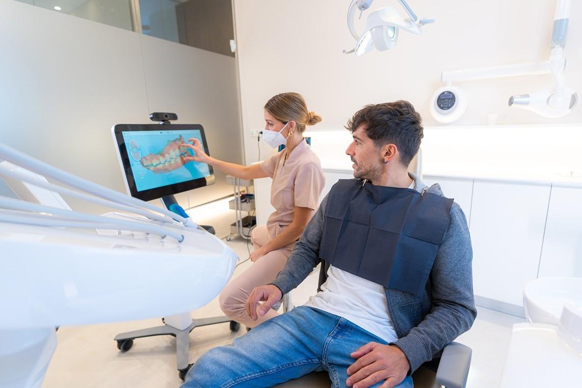 Dentist showing a patient a digital dental scan in a modern exam room.