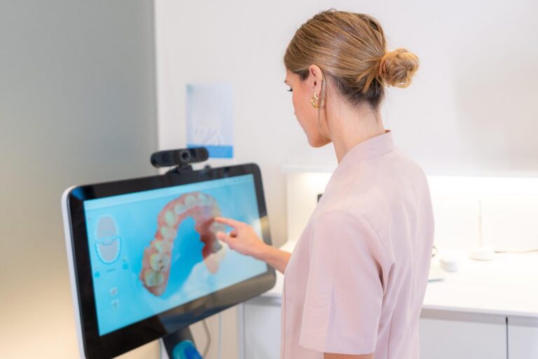 Dentist reviewing 3D dental scan on touchscreen monitor in modern clinic.