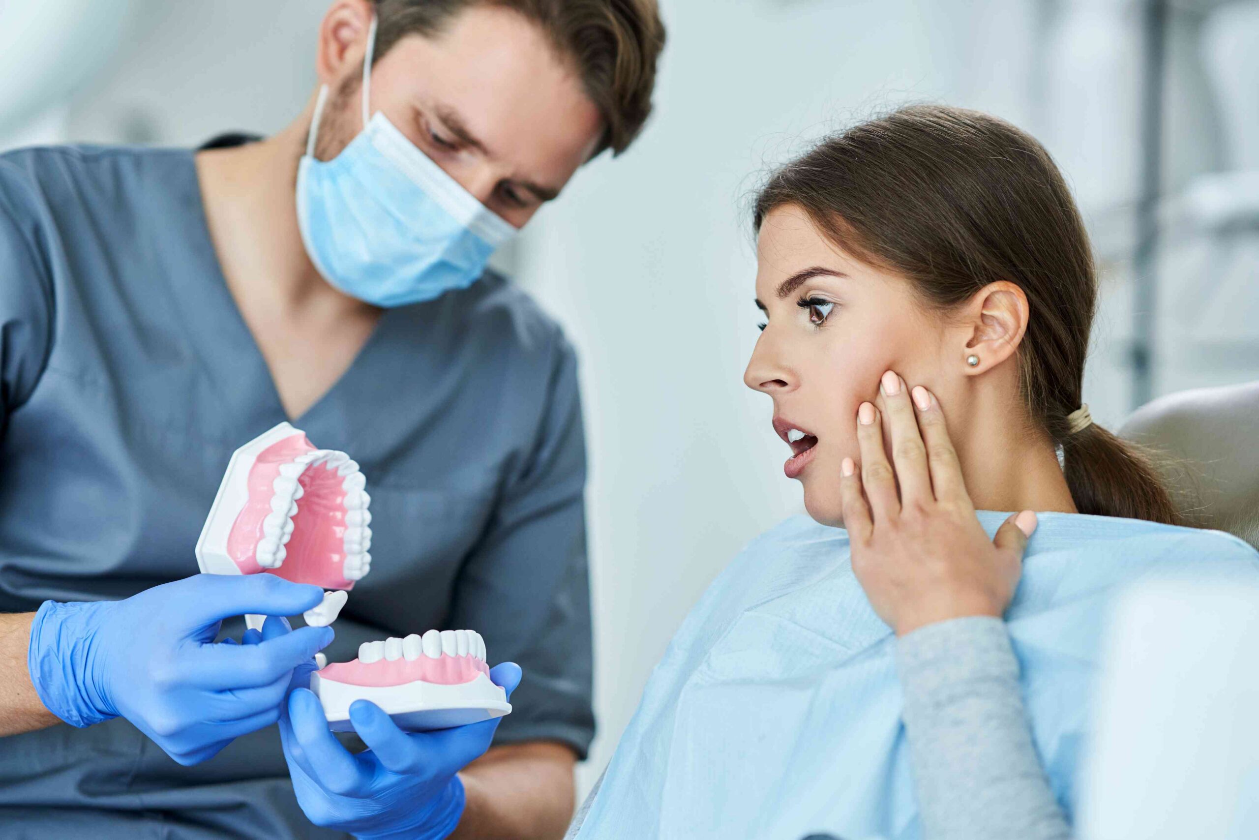 Patient reacting while a dentist explains a dental model.