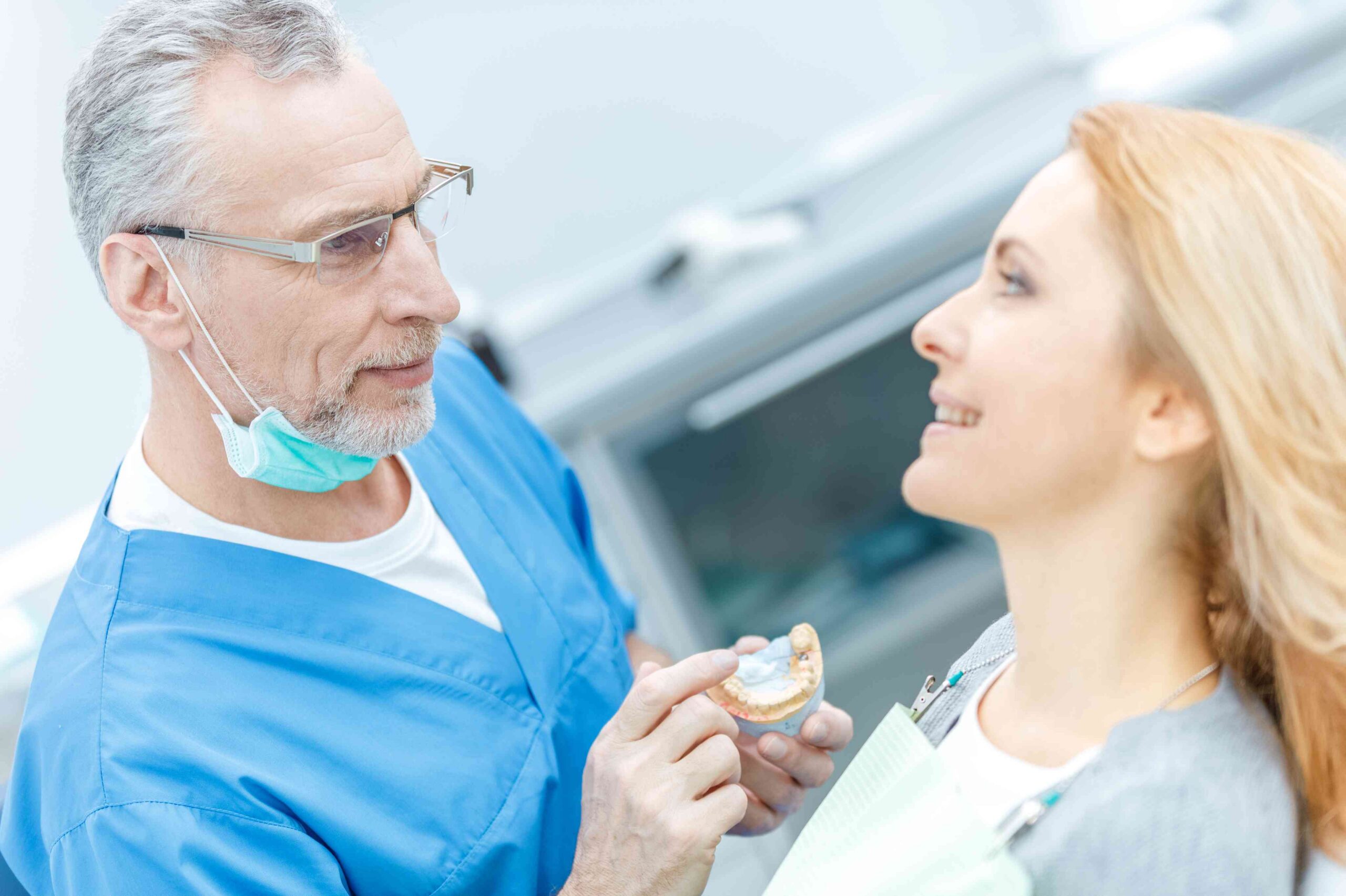 Dentist explaining a dental model to a patient during a consultation.