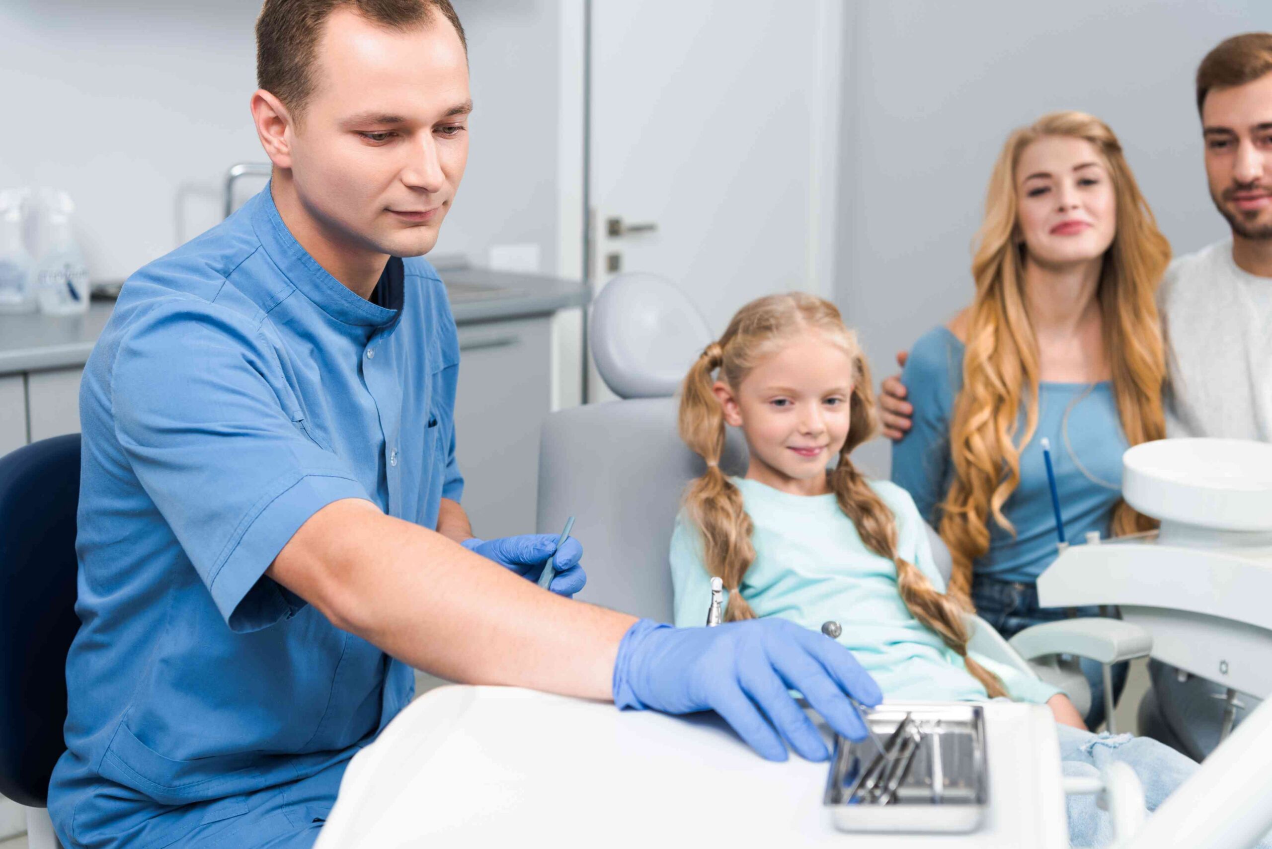 Dentist preparing for a child’s dental visit while parents look on.